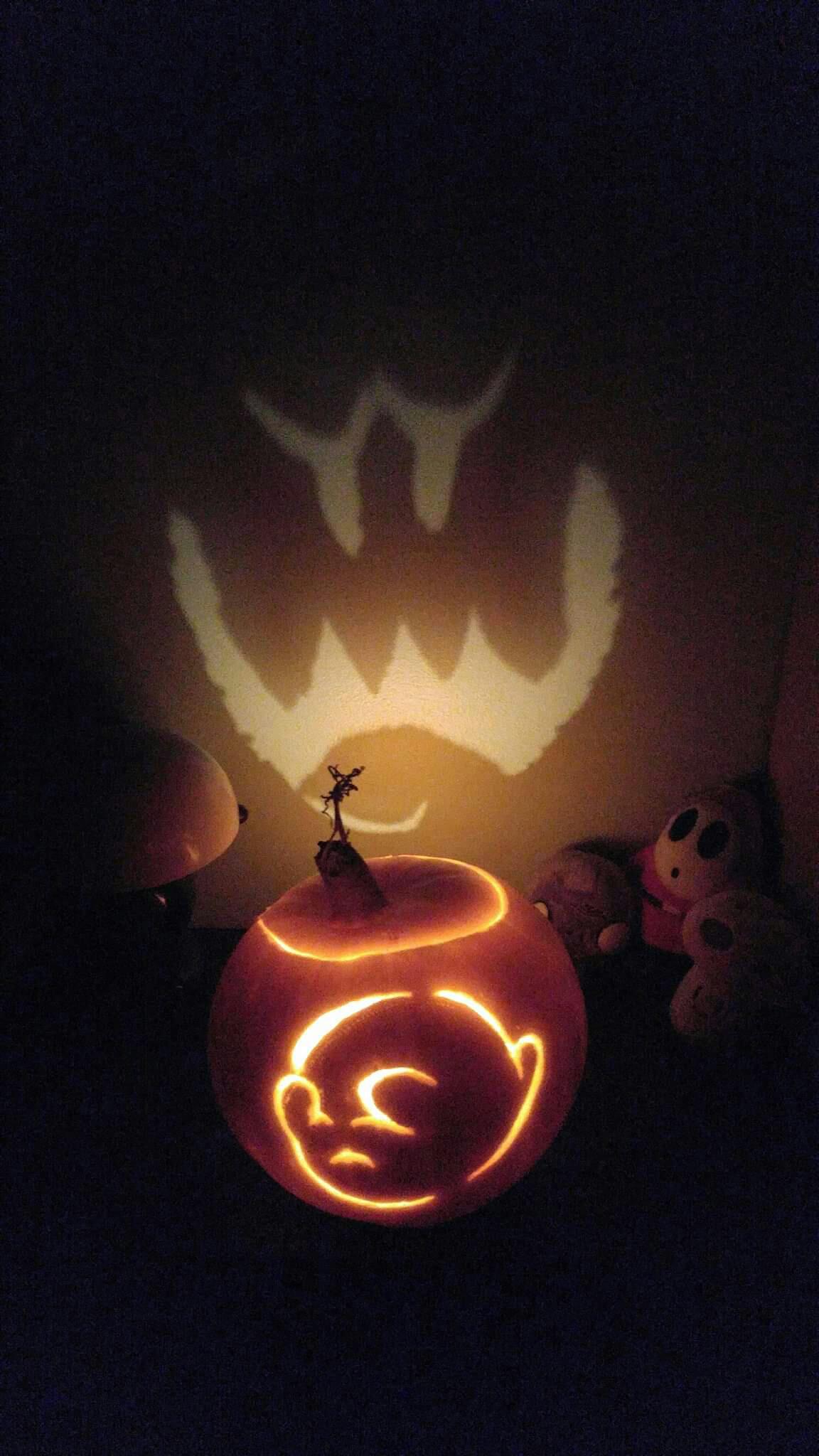 Pumpkin carving of a Boo from Super Mario, a shy round ghost that covers its eyes when looked at. The Boo's revealed face has been carved into the back of the pumpkin, such that it can be seen in the light on the wall behind the pumpkin.